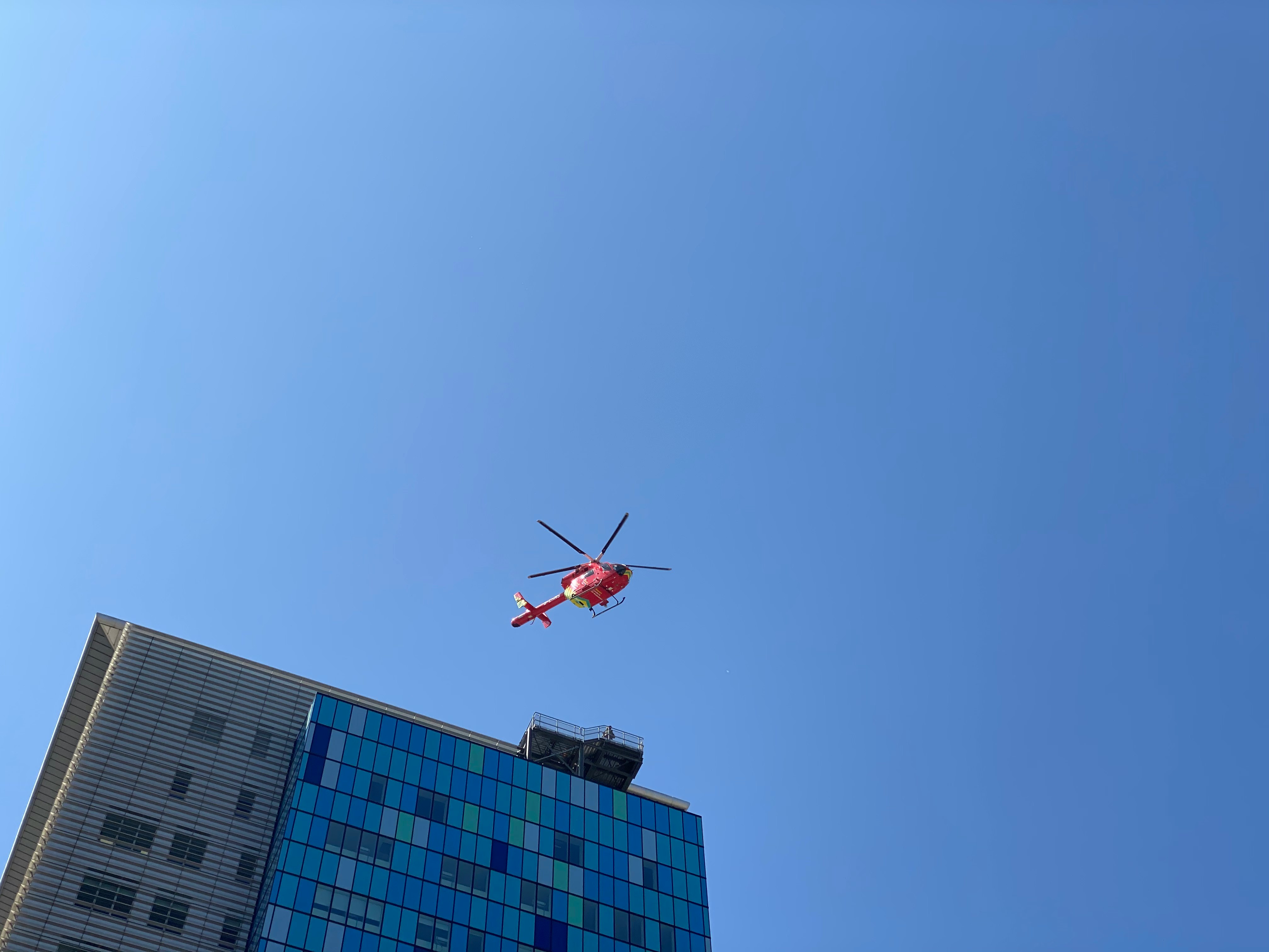red and white helicopter flying over the building during daytime